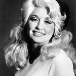 Black-and-white studio portrait of a young Dolly Parton, smiling.