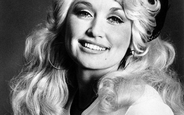 Black-and-white studio portrait of a young Dolly Parton, smiling.