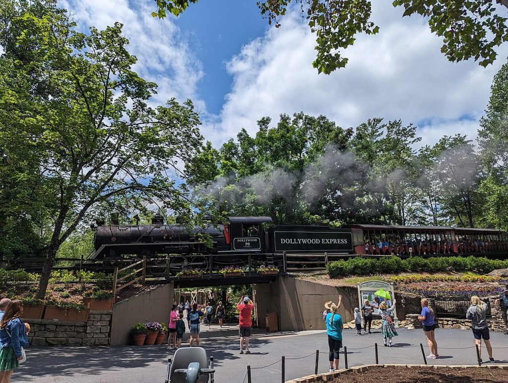 The Dollywood Express steam train rounding a bend as visitors wave.