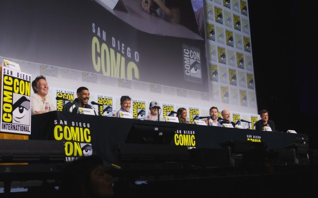 The cast and creators of HBO's Lanterns on stage at the San Diego Comic-Con 2026 panel, seated behind a Comic-Con backdrop.
