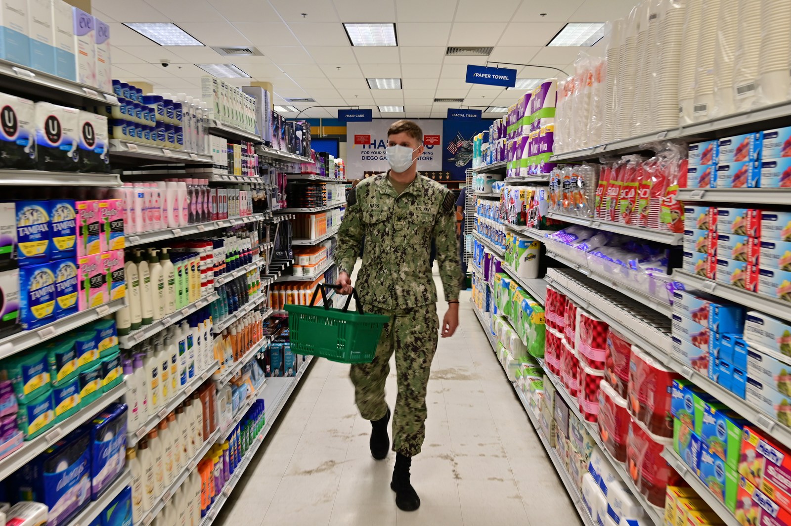 A U.S. sailor carries a shopping basket down a stocked aisle of toiletries at the Navy base store on Diego Garcia