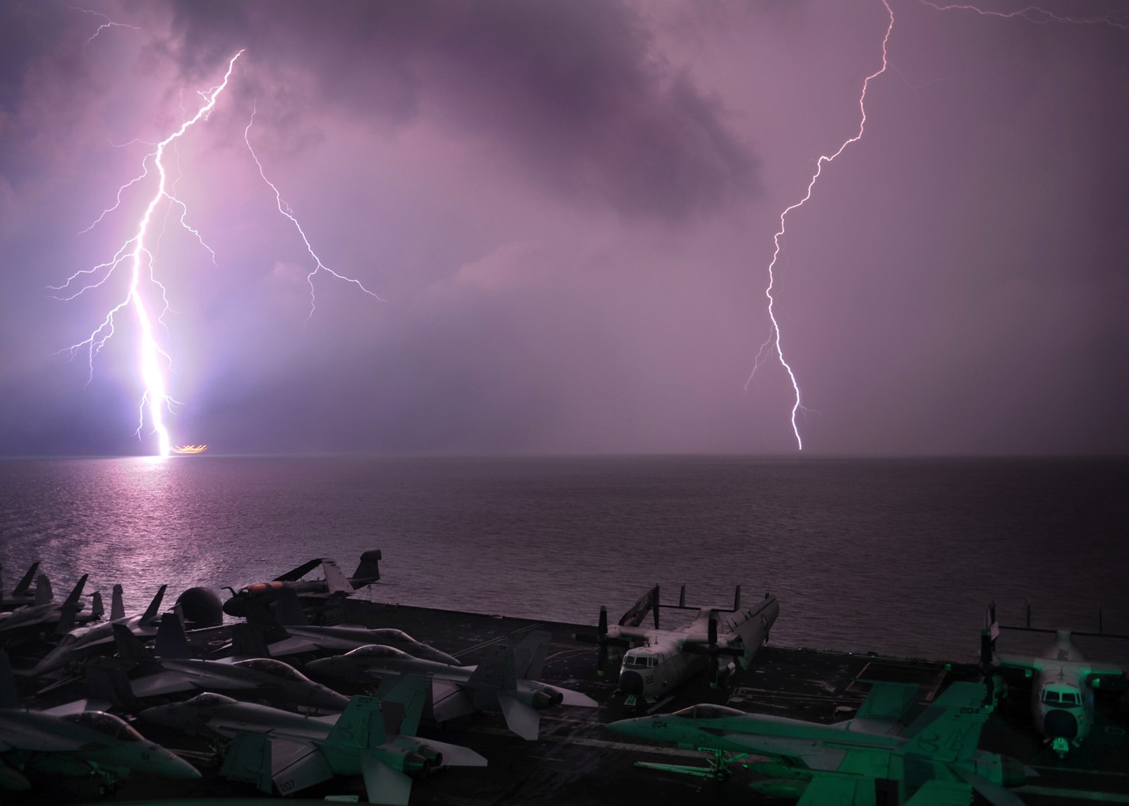 Lightning strikes the sea beyond aircraft parked on the flight deck of USS Abraham Lincoln during a night storm