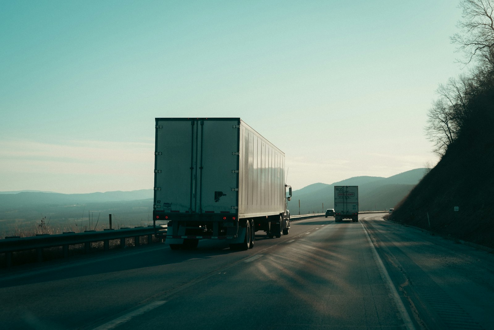 Two freight semi-trucks driving on a highway.