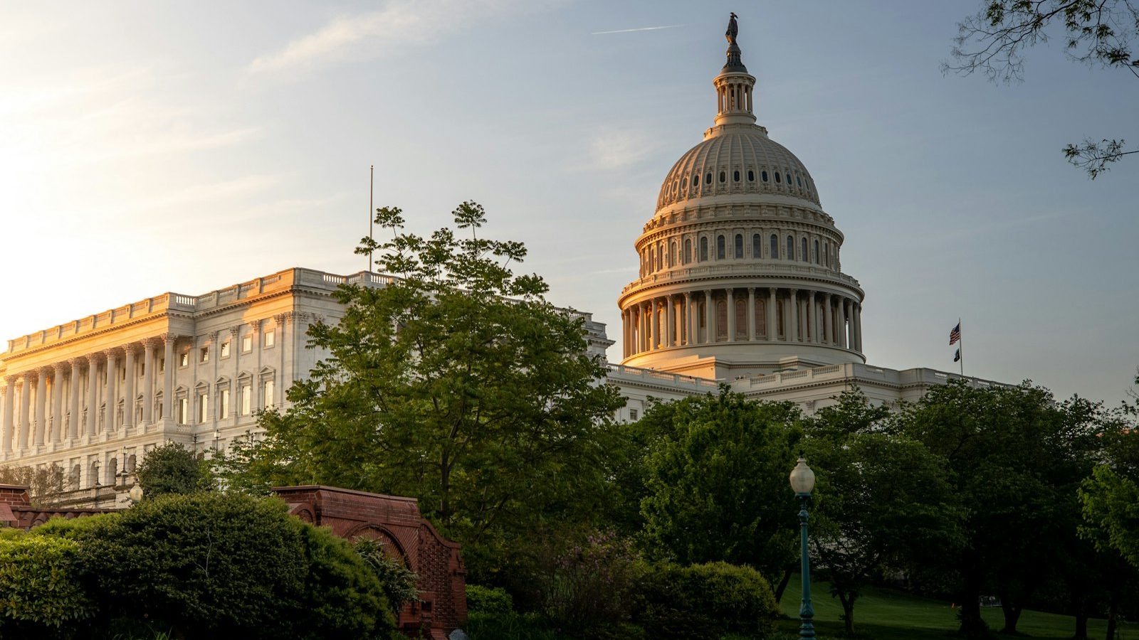 The dome of the United States Capitol lit gold at sunset against a deep blue sky.