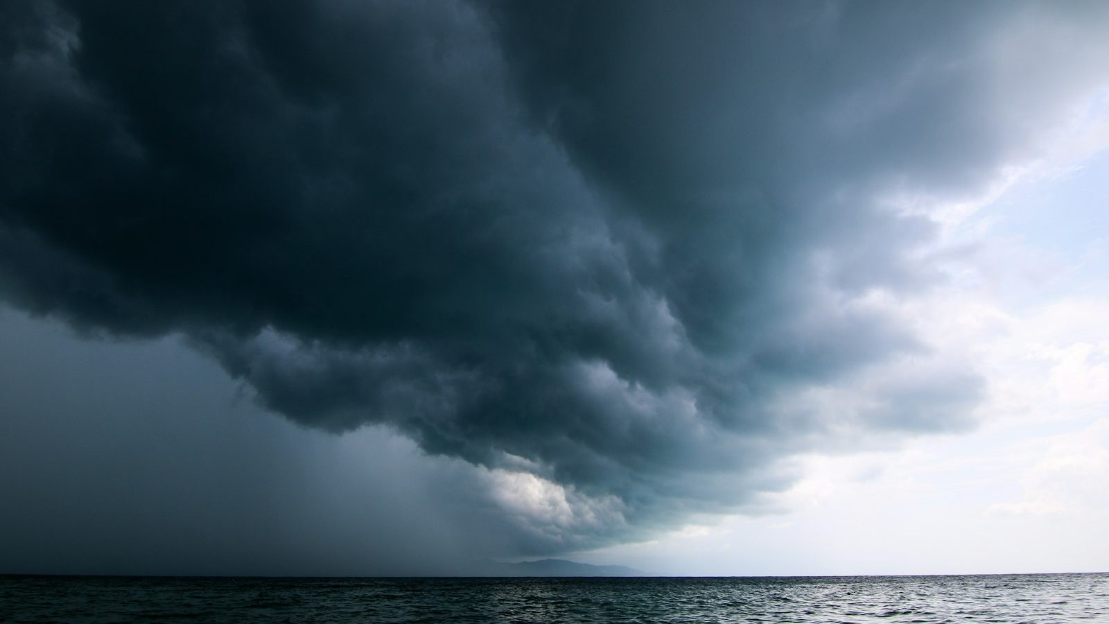 A large storm system moving across the sky over open water.