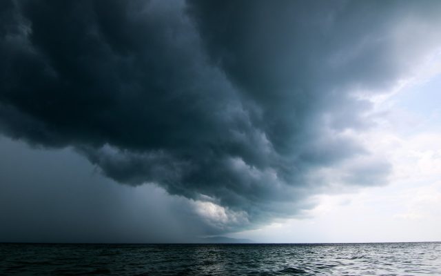A large storm system moving across the sky over open water.