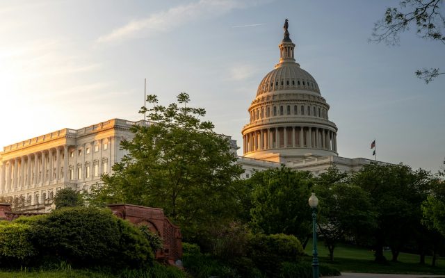 The dome of the United States Capitol lit gold at sunset against a deep blue sky.
