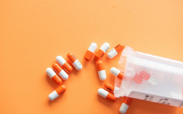 A single orange-and-white medication capsule on a plain white surface.