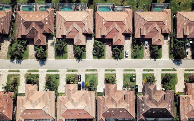 Aerial view of rows of single-family homes with tile roofs and pools in a Florida residential neighborhood