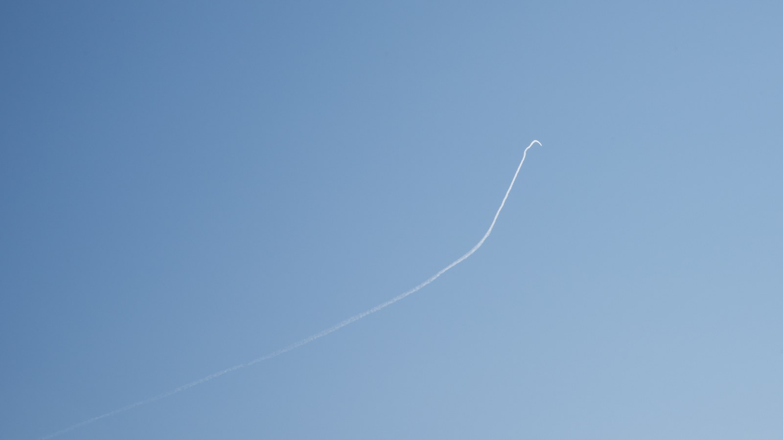 A jet's white contrail traces a long line across a clear blue sky during a 2018 NASA flight campaign.