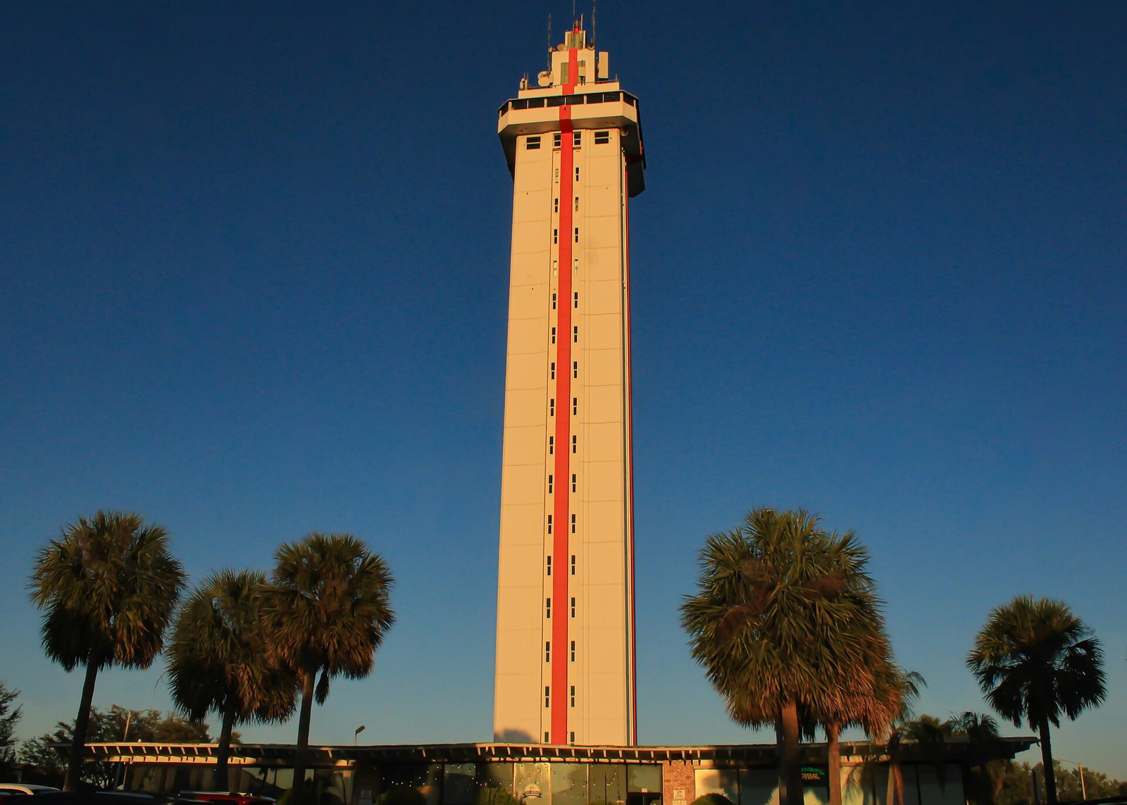 The tall Florida Citrus Tower in Clermont lit by the setting sun, with palm trees