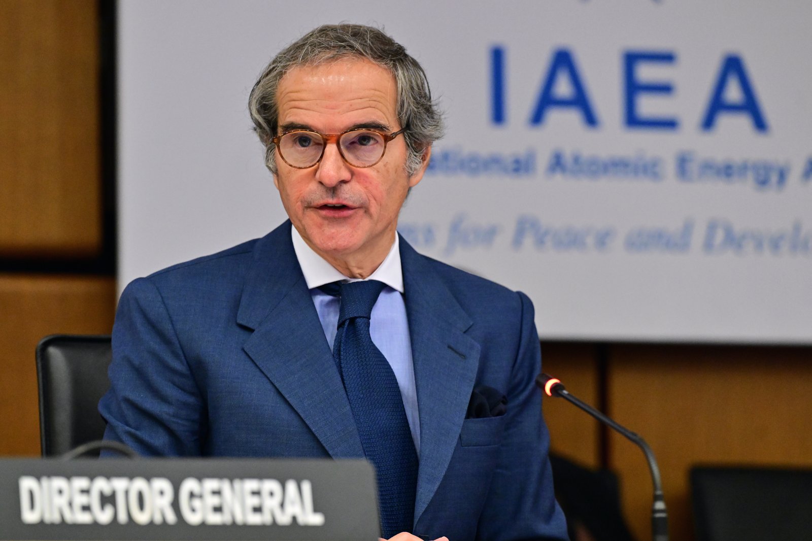 IAEA Director General Rafael Mariano Grossi speaks behind a Director General nameplate in front of an IAEA banner