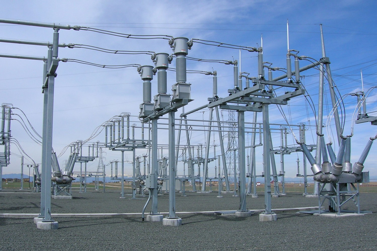 A high-voltage electrical substation with steel bus bars, transformers and switchgear under an open sky.