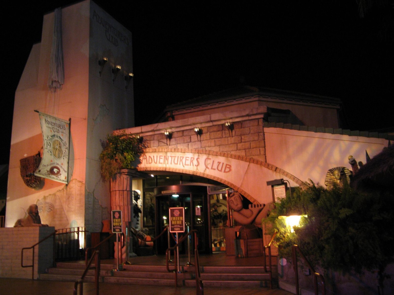 The Adventurers Club entrance at night on Pleasure Island, with a banner and lanterns