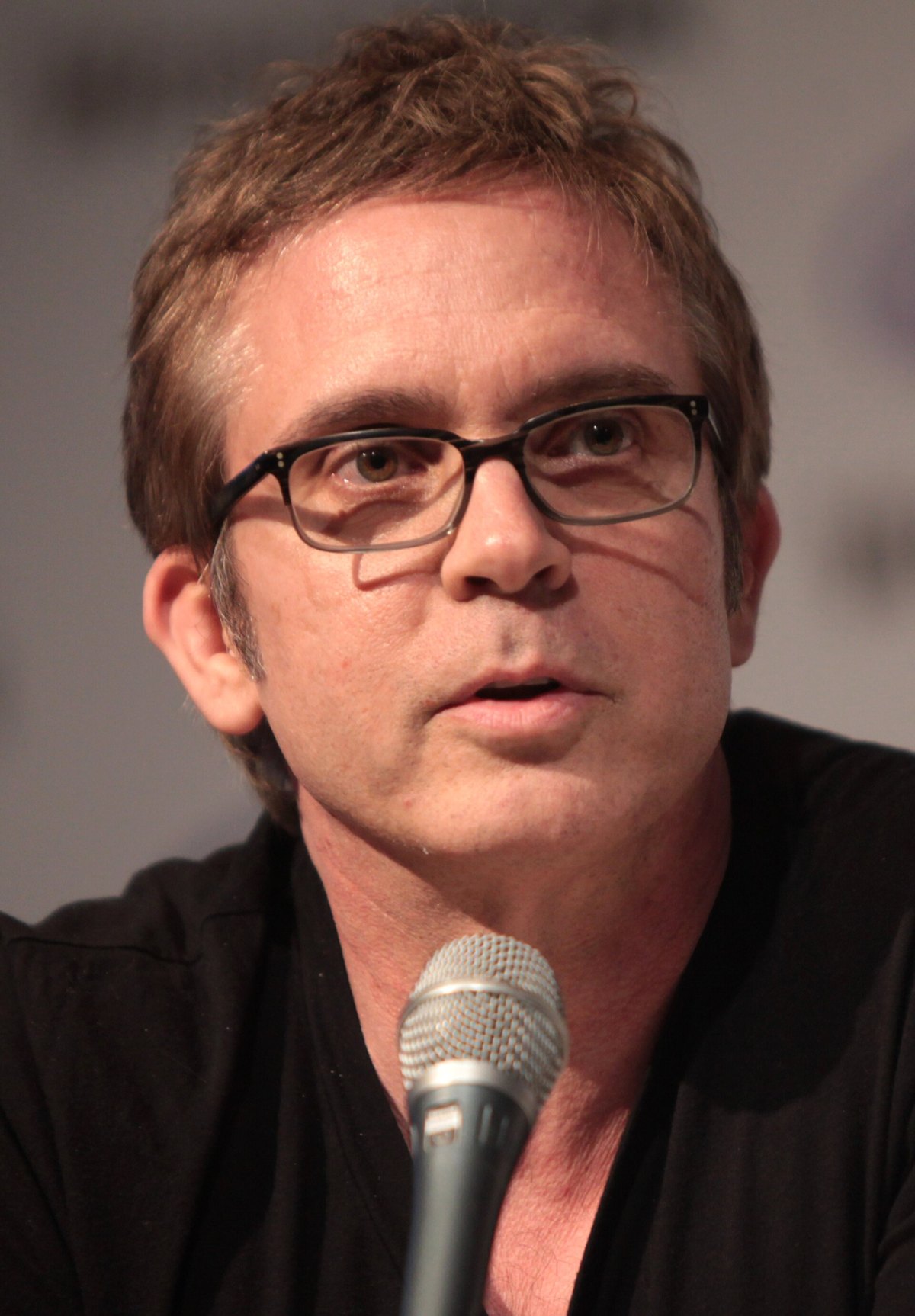 Brannon Braga in glasses speaking into a microphone at a convention panel