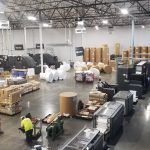 Sheets of official election ballots moving through a commercial printing press.