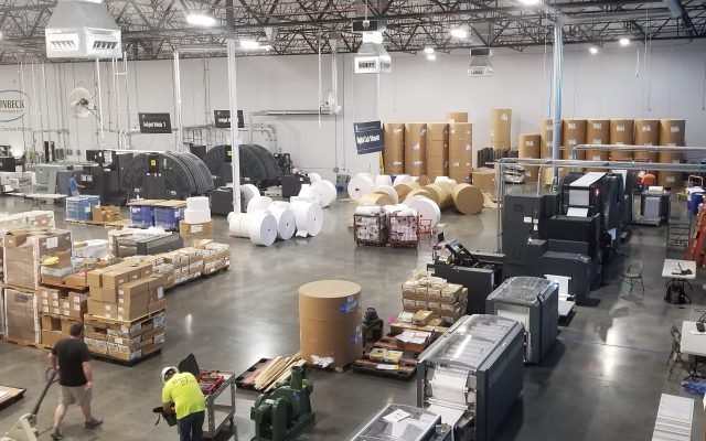 Sheets of official election ballots moving through a commercial printing press.
