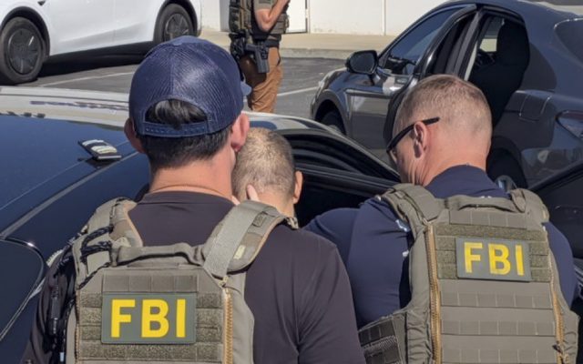Two FBI agents escort Greg Lui beside a car during his arrest in Los Angeles County.
