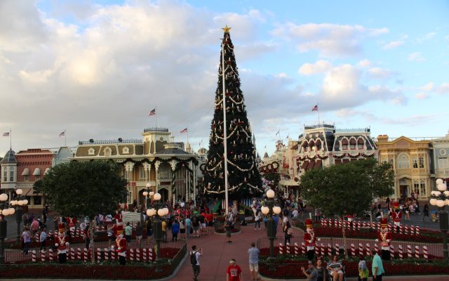 The giant Christmas tree in Town Square at Magic Kingdom, ringed by toy soldier figures and red-and-white fencing, with Main Street buildings behind it