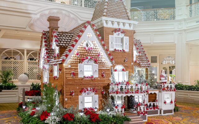 A large gingerbread house decorated for Christmas inside a Walt Disney World resort lobby.